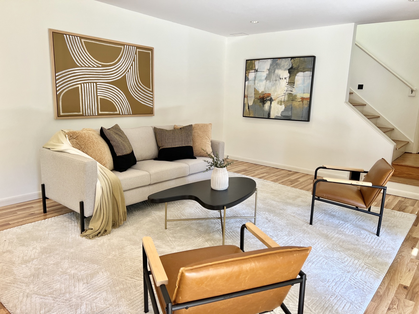 Open living room with a staircase and curated art, professionally staged